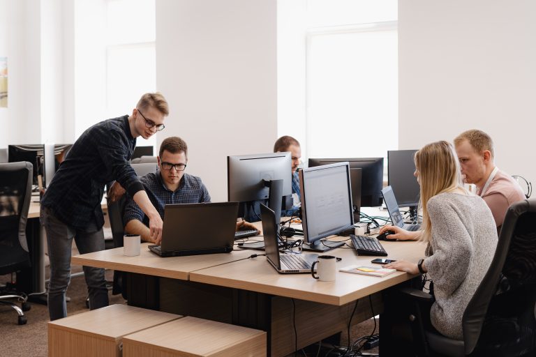 A pleasant, bright, modern office space under daylight with midwest professionals cooperating smoothly on laptops
